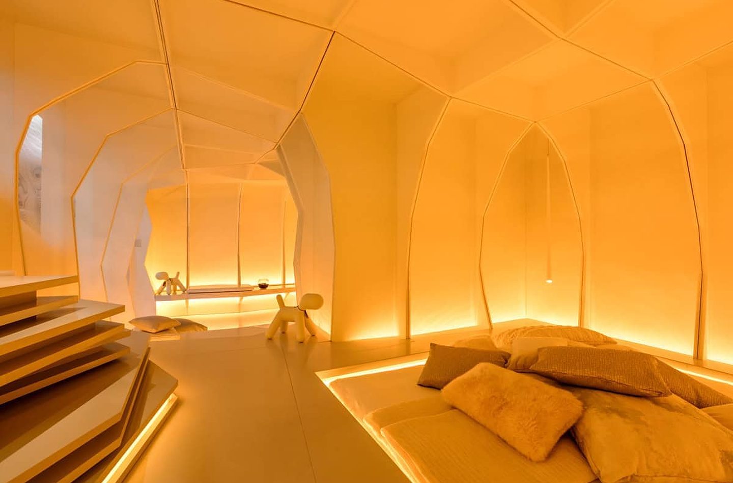 A curved white room lit by warm LED strip lighting along the floor and walls